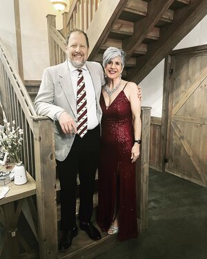 A finely dressed couple standing at bottom of a wooden staircase is your Hatchery House hosts out on the town supporting the Weston Community Theatre.