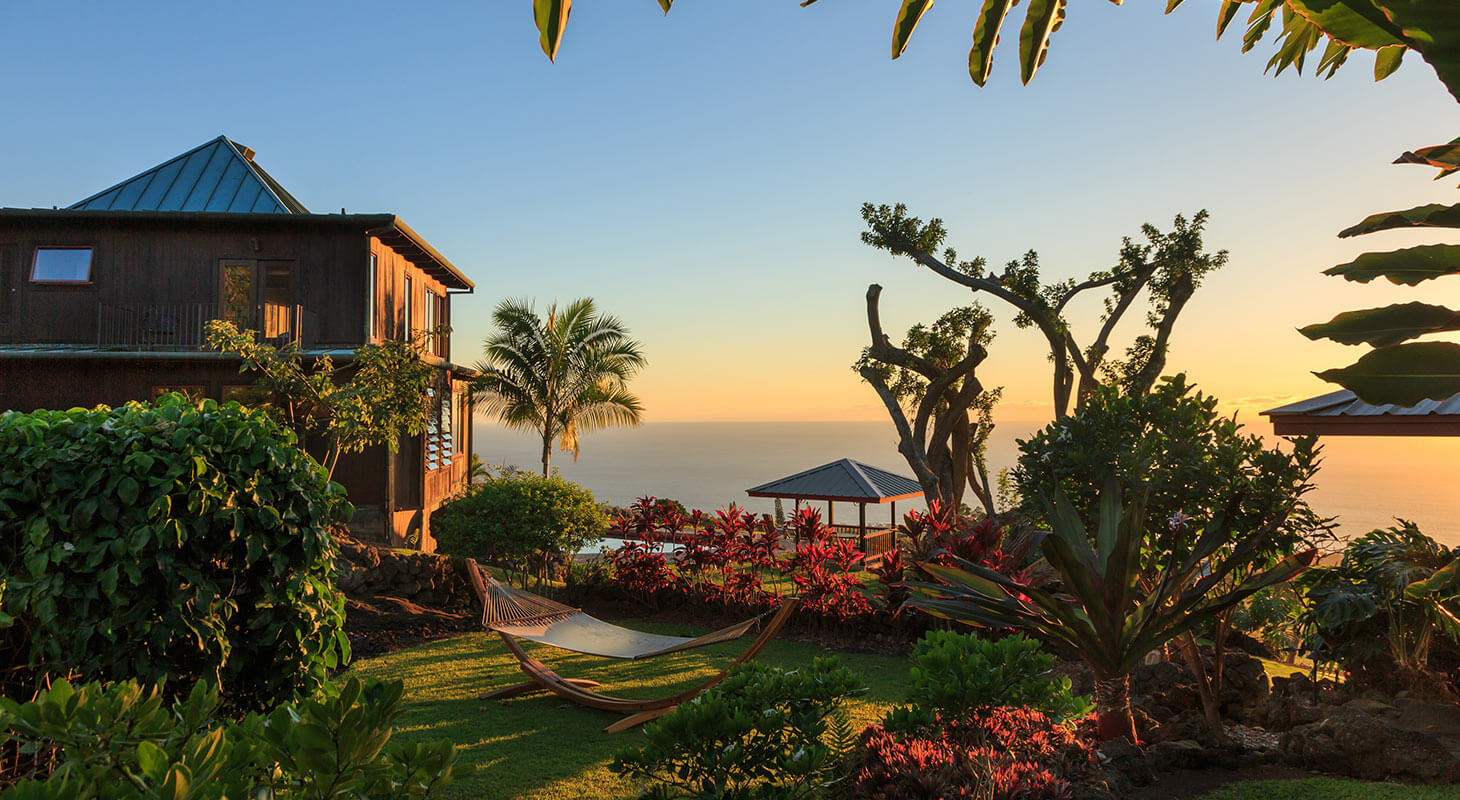 Holualoa gardens at sunset with hammock, flowers, and inn building