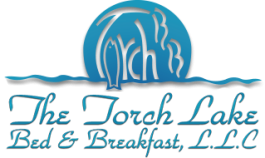 Logo for The Torch Lake Bed & Breakfast, L.L.C., featuring a blue sun with a fish and water design above the name in elegant script, capturing the tranquil charm of this torch lake bed and breakfast.